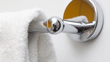 A white towel hanging on a chrome towel bar attached to a wall.