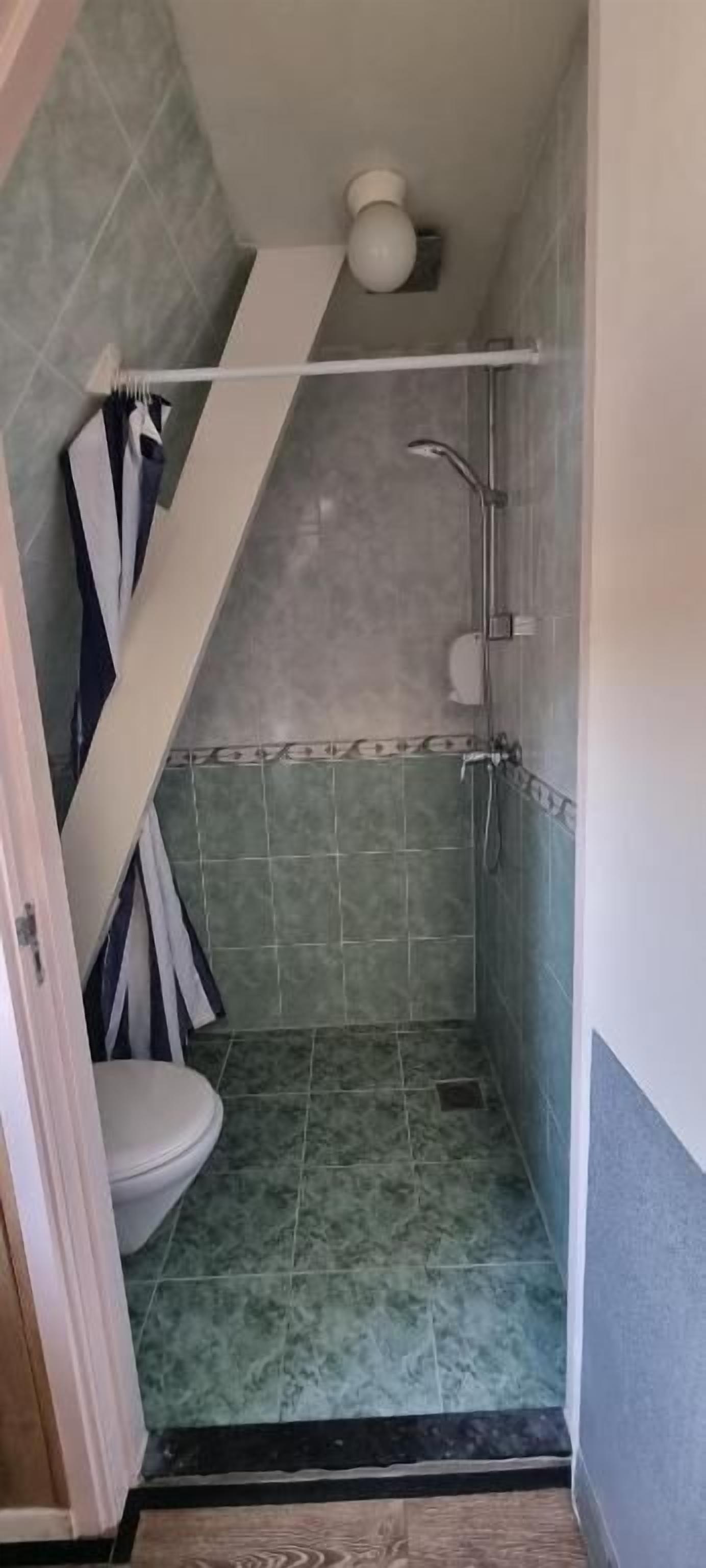 A small bathroom with a toilet, shower, and a towel rack.
