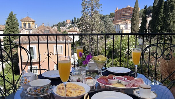 Una mesa con comida y bebidas en un balcón con vistas a un pueblo.