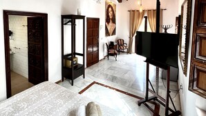 Una habitación de hotel con una cama grande, televisor y techo de madera.