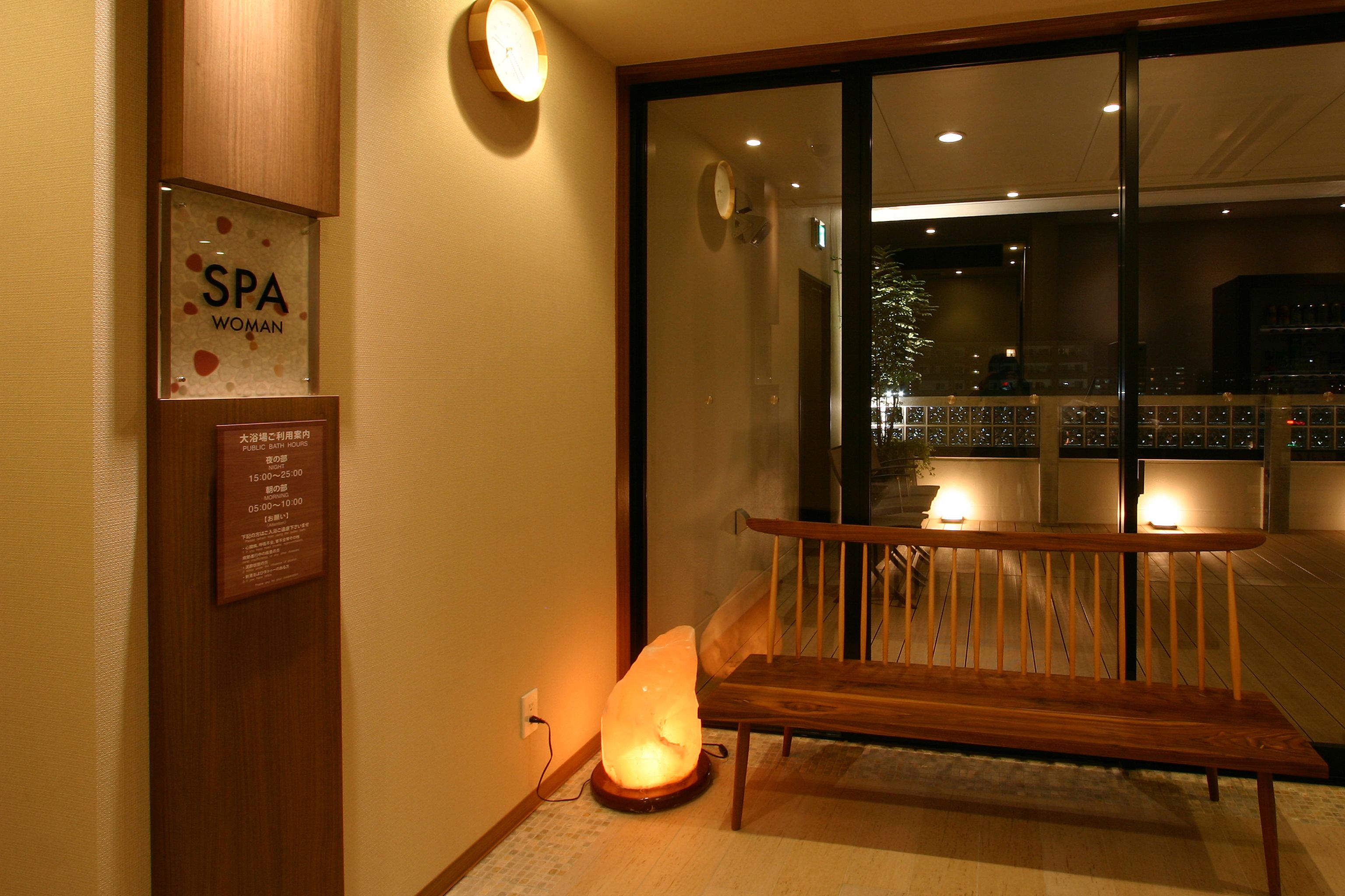 Un área de spa con un banco de madera, una lámpara de sal y un cartel que indica servicios de spa.