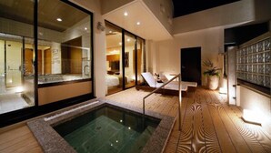 A modern hotel room with a private balcony, a hot tub, and a view of the interior.