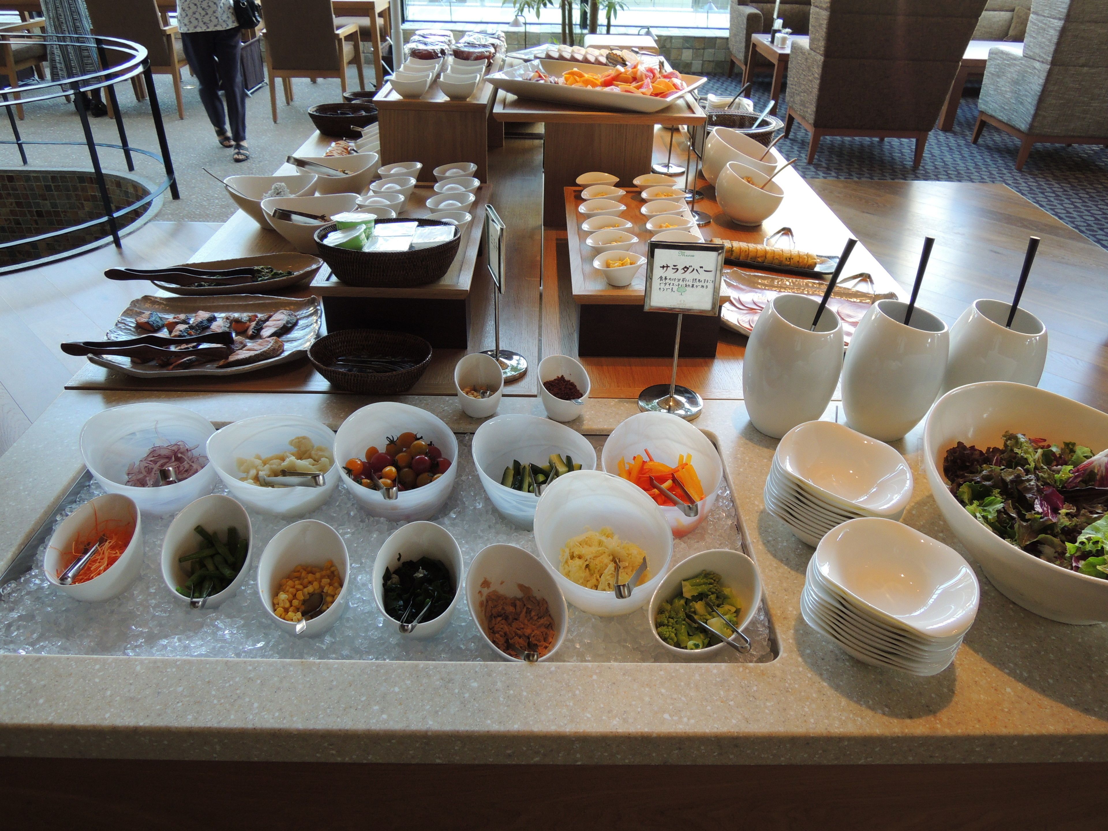 A buffet with various food items and bowls of condiments.