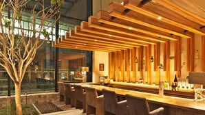 A modern bar area with a long counter, multiple seating options, and a large window offering a view of the outside.