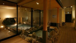 A spa area with a hot tub, wooden flooring, and a glass partition.