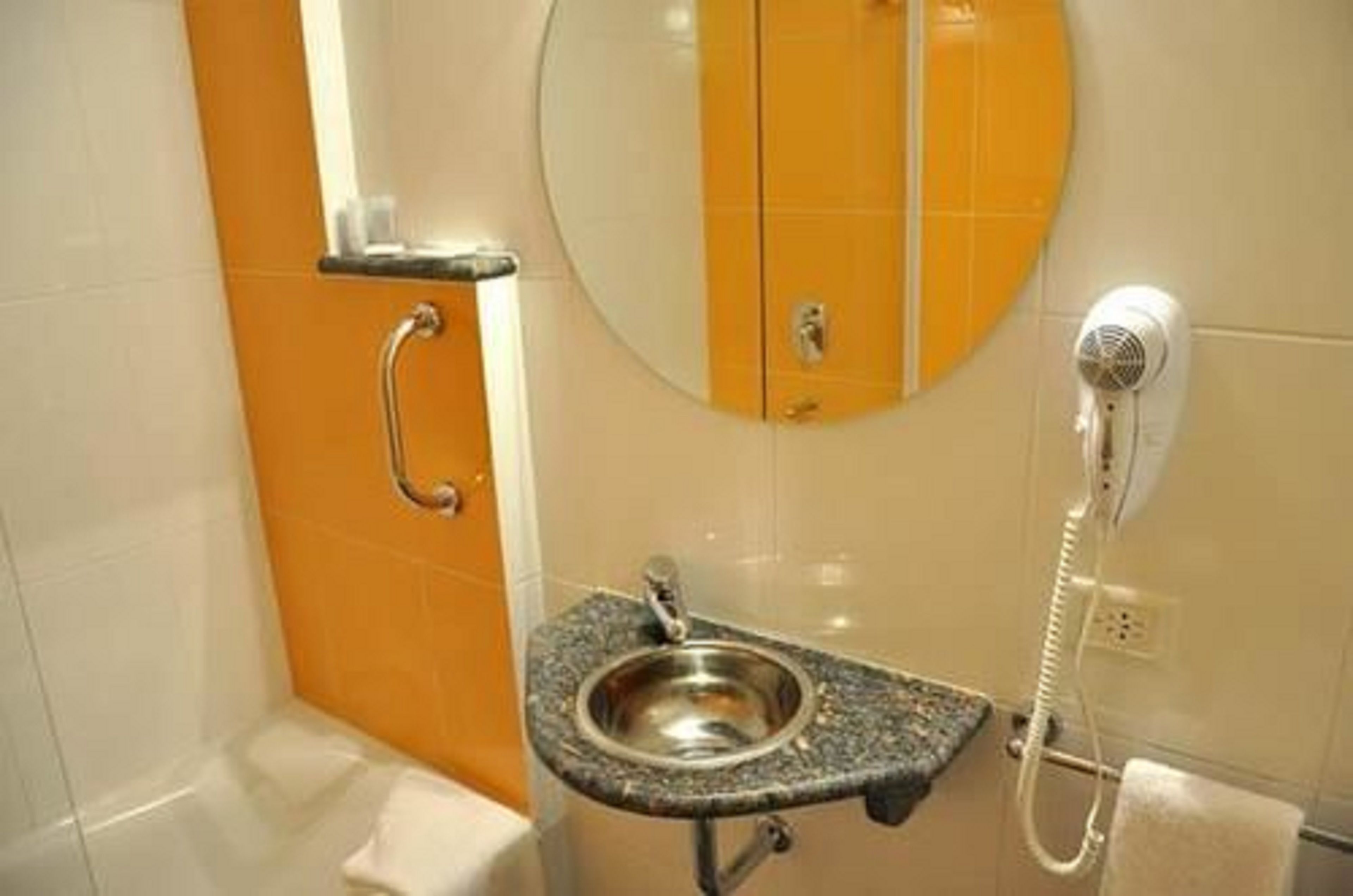 A bathroom with a sink, mirror, and a hairdryer on the wall.