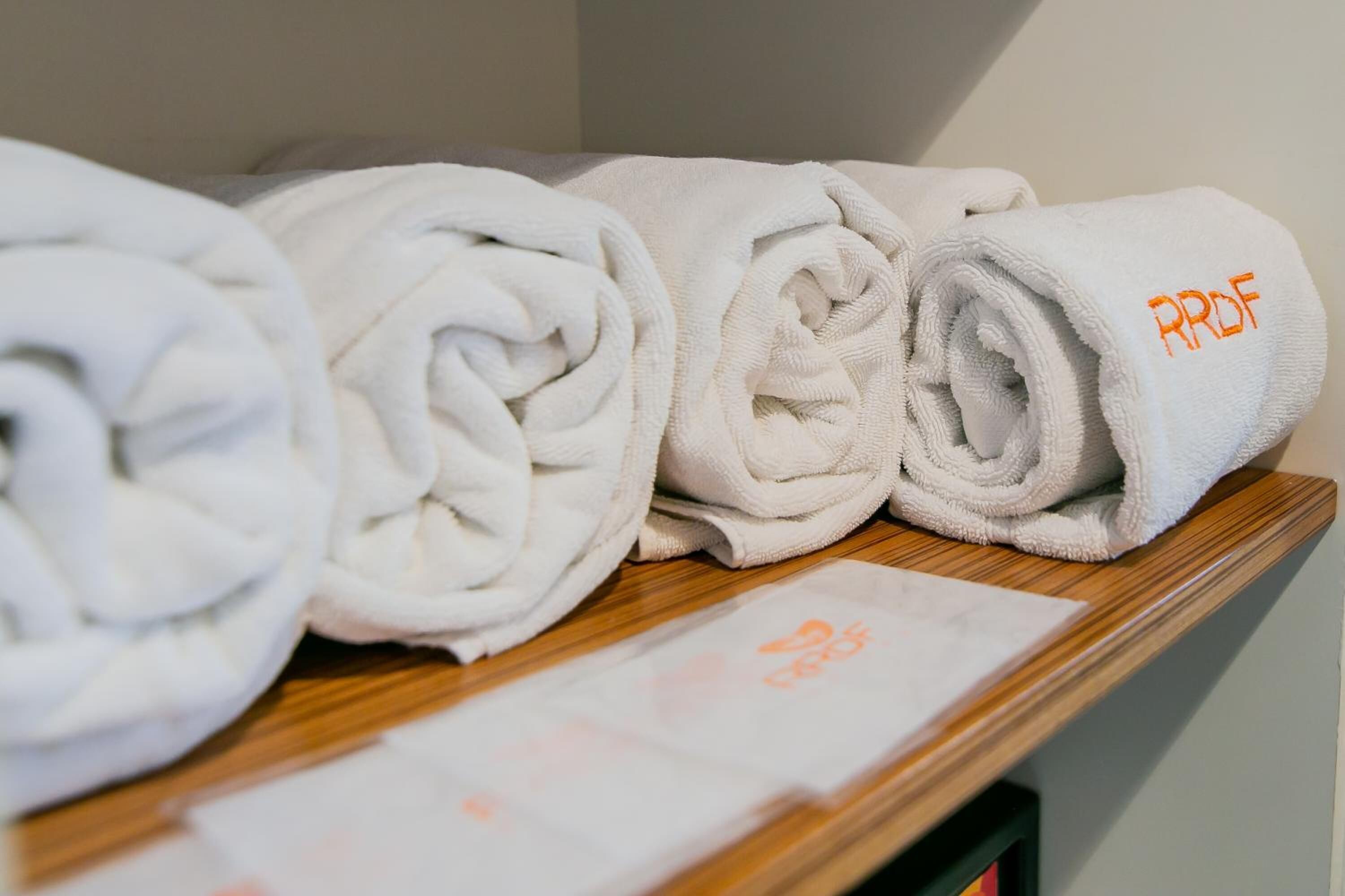 A row of neatly folded white towels with embroidered text on a wooden shelf.