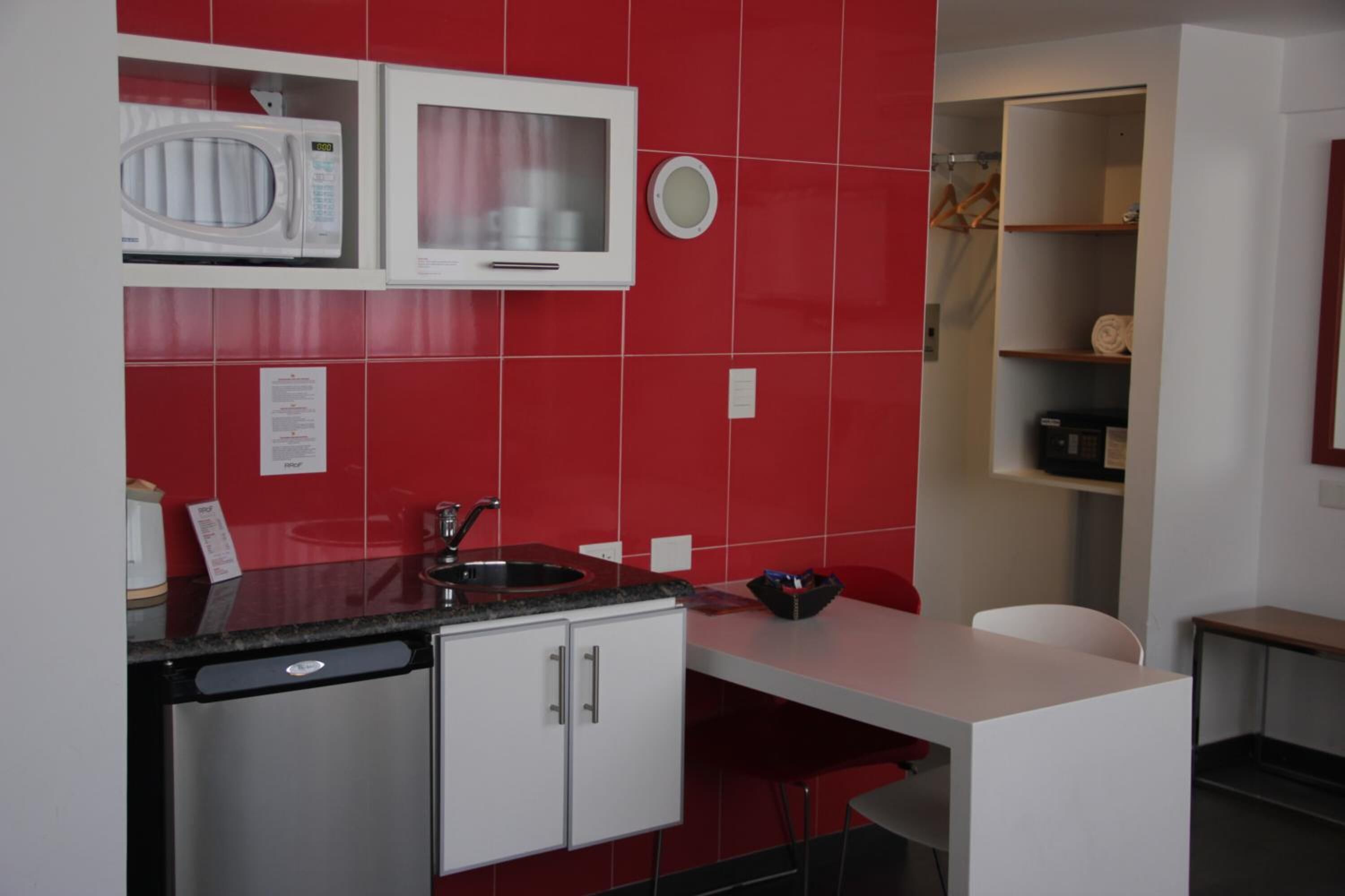 A compact kitchen with a microwave, sink, and cabinets.