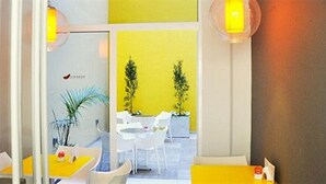 A modern interior with a yellow and white color scheme, featuring a dining area with white chairs and a table, and a seating area with a yellow sofa. - Roberta Rosa de Fontana Suites (Rosario)