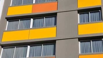 Un edificio de varios pisos con un diseño arquitectónico moderno, que presenta una serie de balcones con cortinas.