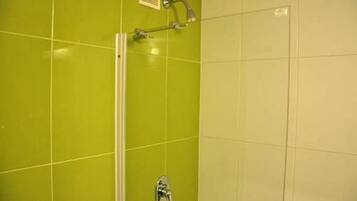 Un baño con baldosas verdes y zona de ducha.