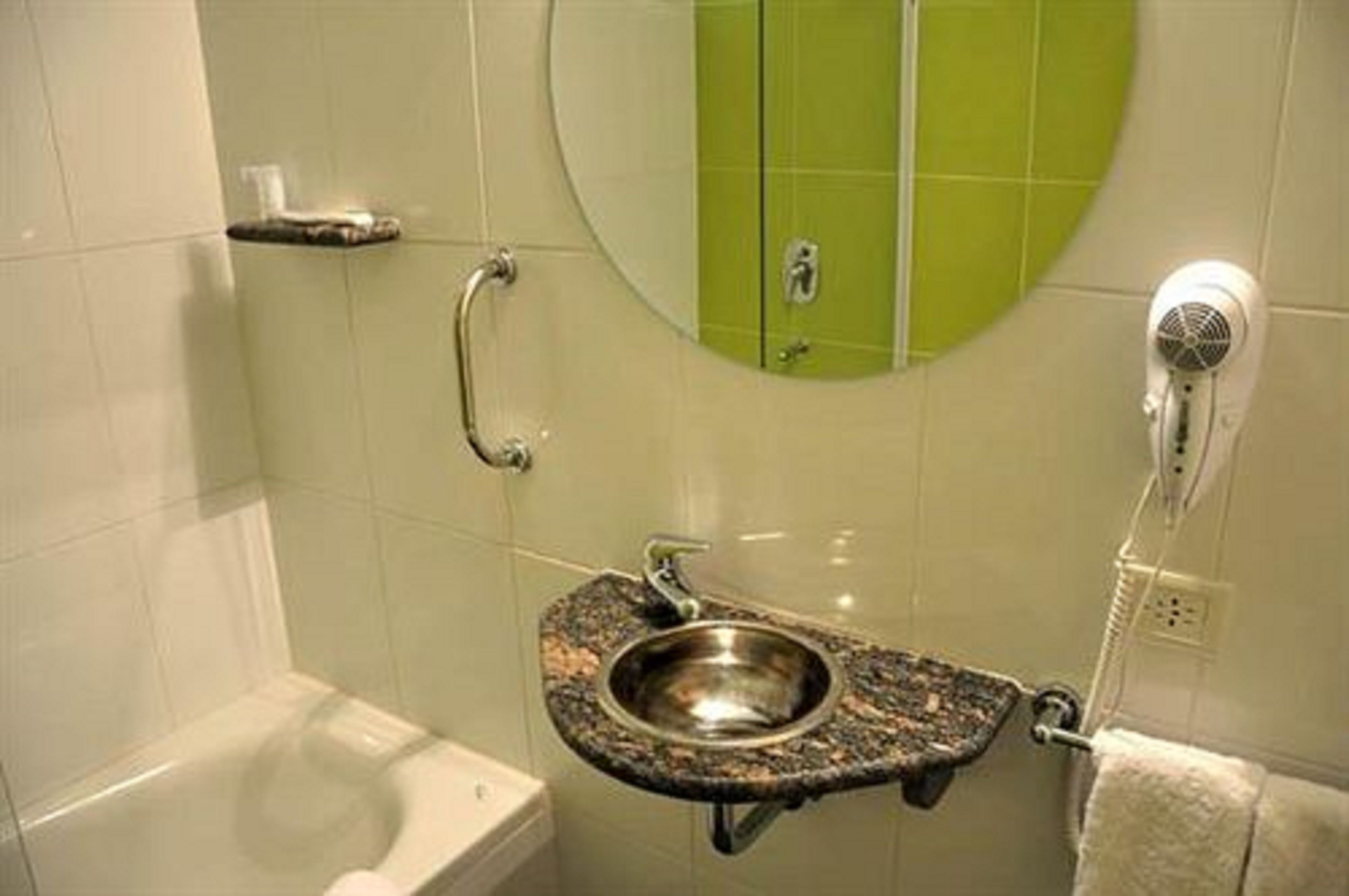 A bathroom with a sink, toilet, and a hairdryer mounted on the wall.