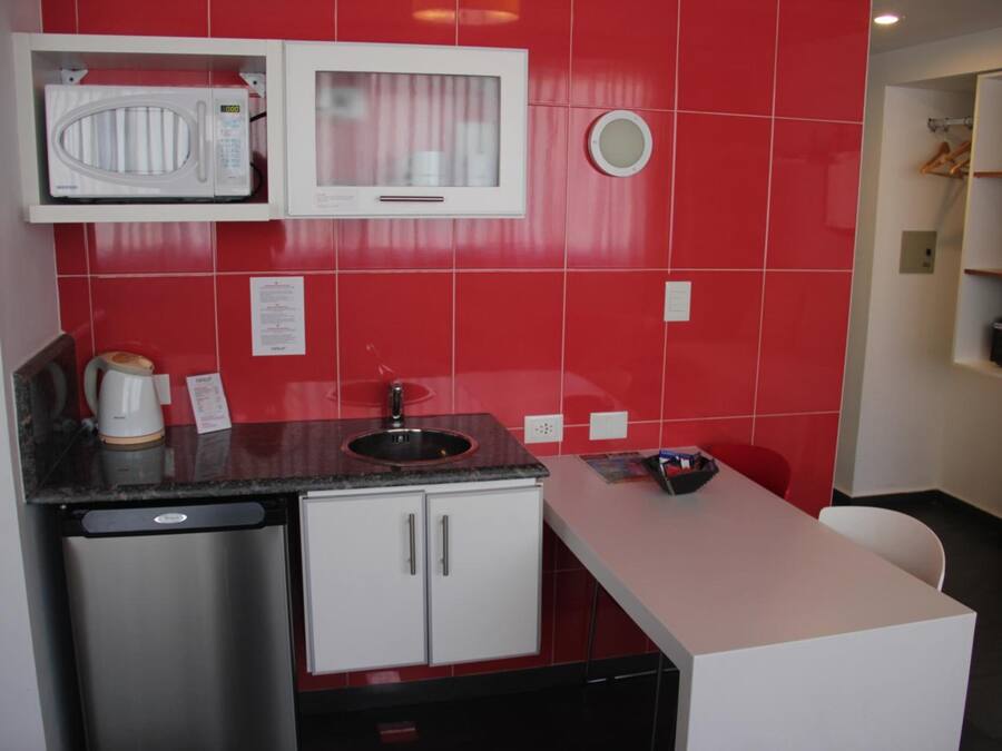 Cozinha compacta com micro-ondas, pia e pequena geladeira.