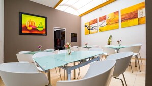A modern conference room with glass tables and white chairs, featuring abstract paintings on the walls. - Ayenda 1703 Gran Reserva (Villavicencio)