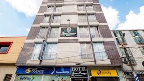 A hotel building with multiple floors, balconies, and various business signs on the ground floor. - Ayenda 1703 Gran Reserva (Villavicencio)