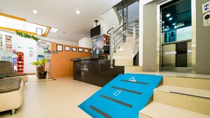 A hotel lobby with a reception desk, a staircase, and a blue ramp with accessibility symbols. - Ayenda 1703 Gran Reserva (Villavicencio)