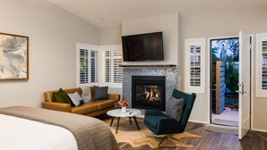 A modern bedroom with a fireplace, a bed, a sofa, and a TV. - Olea Hotel (Glen Ellen)