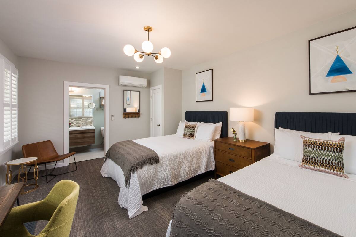 A hotel room with a large bed, a bedside table, a chair, and a desk.