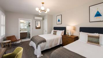 A hotel room with a large bed, a bedside table, a chair, and a desk.