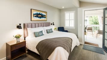 A bedroom with a bed, nightstand, lamp, and artwork.