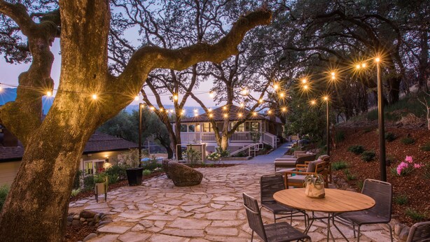 A stone patio with outdoor seating and string lights. - Olea Hotel (Glen Ellen)