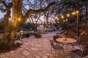 A stone patio with outdoor seating and string lights. - Olea Hotel (Glen Ellen)