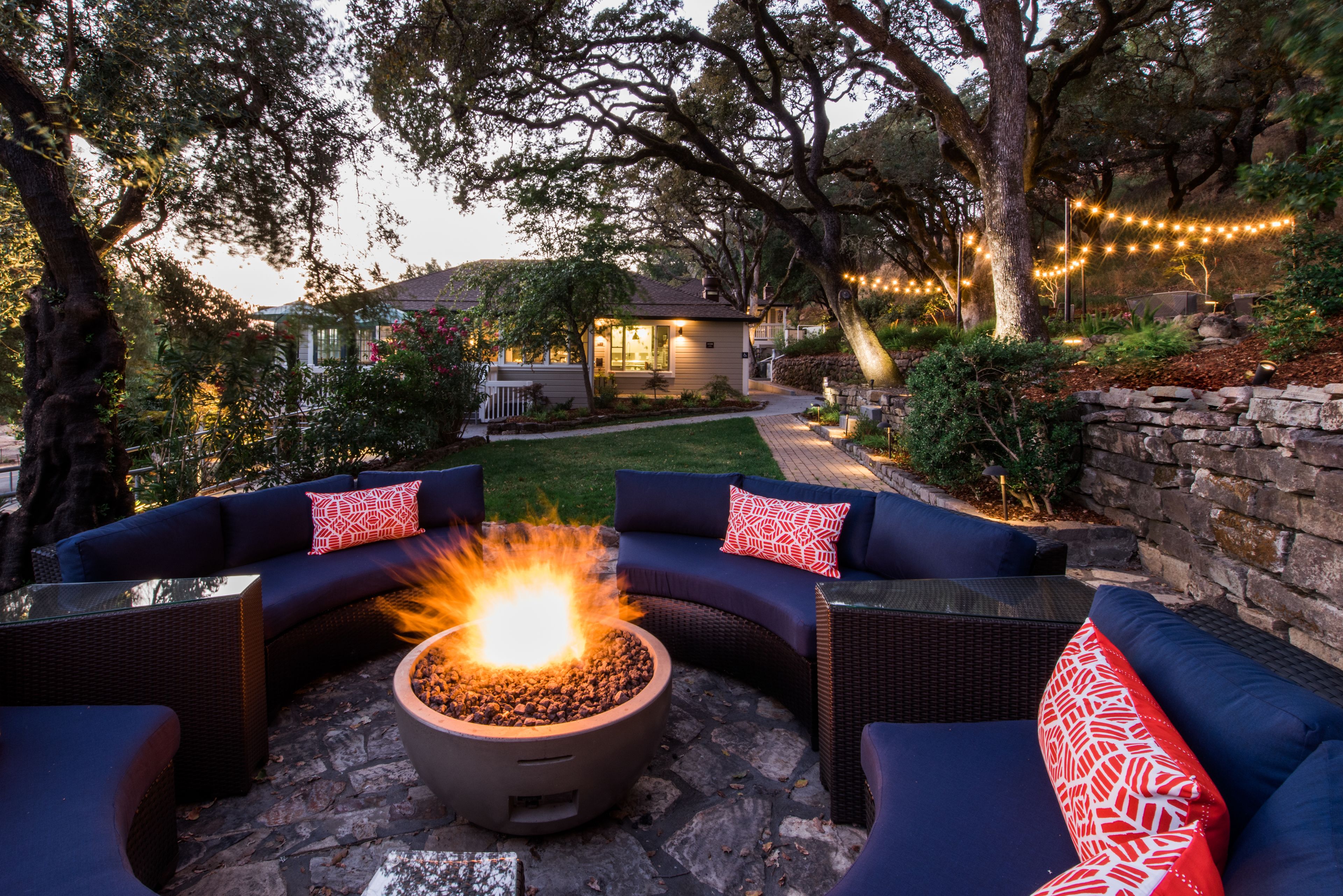 A patio area with a fire pit, outdoor furniture, and string lights.