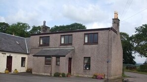 A two-story building with a flat roof, a chimney, and a small porch area with potted plants. - Dykefield Farm B&B (Mauchline)