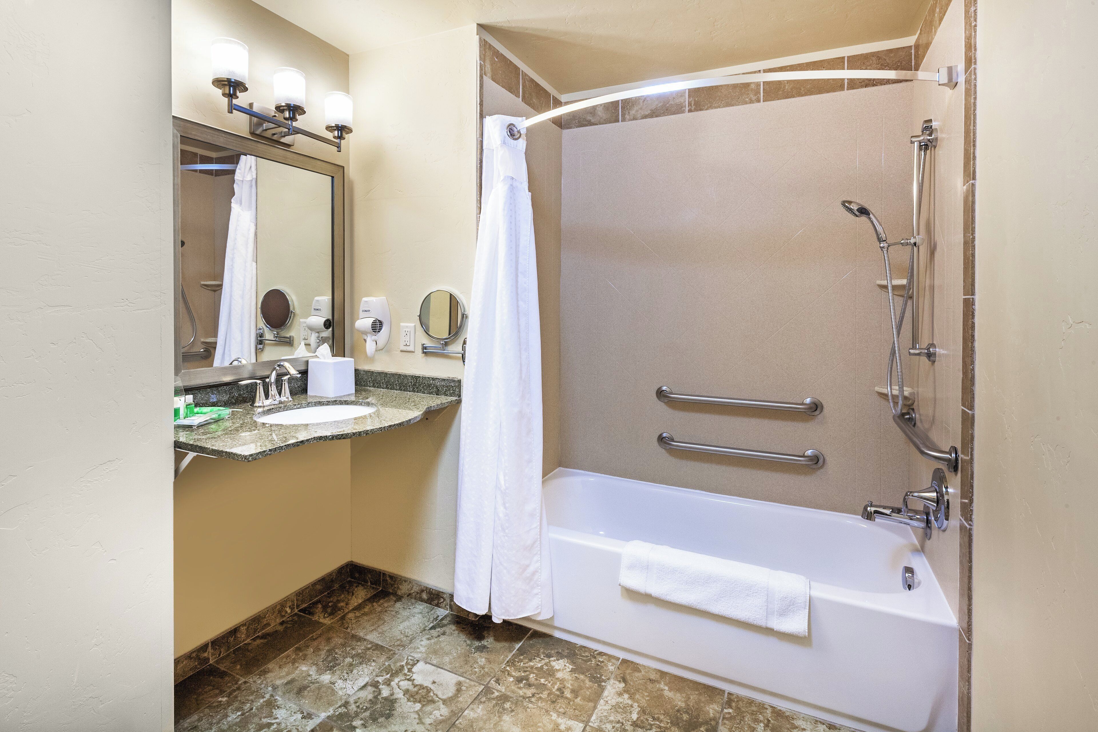 A bathroom with a bathtub, a shower, a sink, and a mirror.