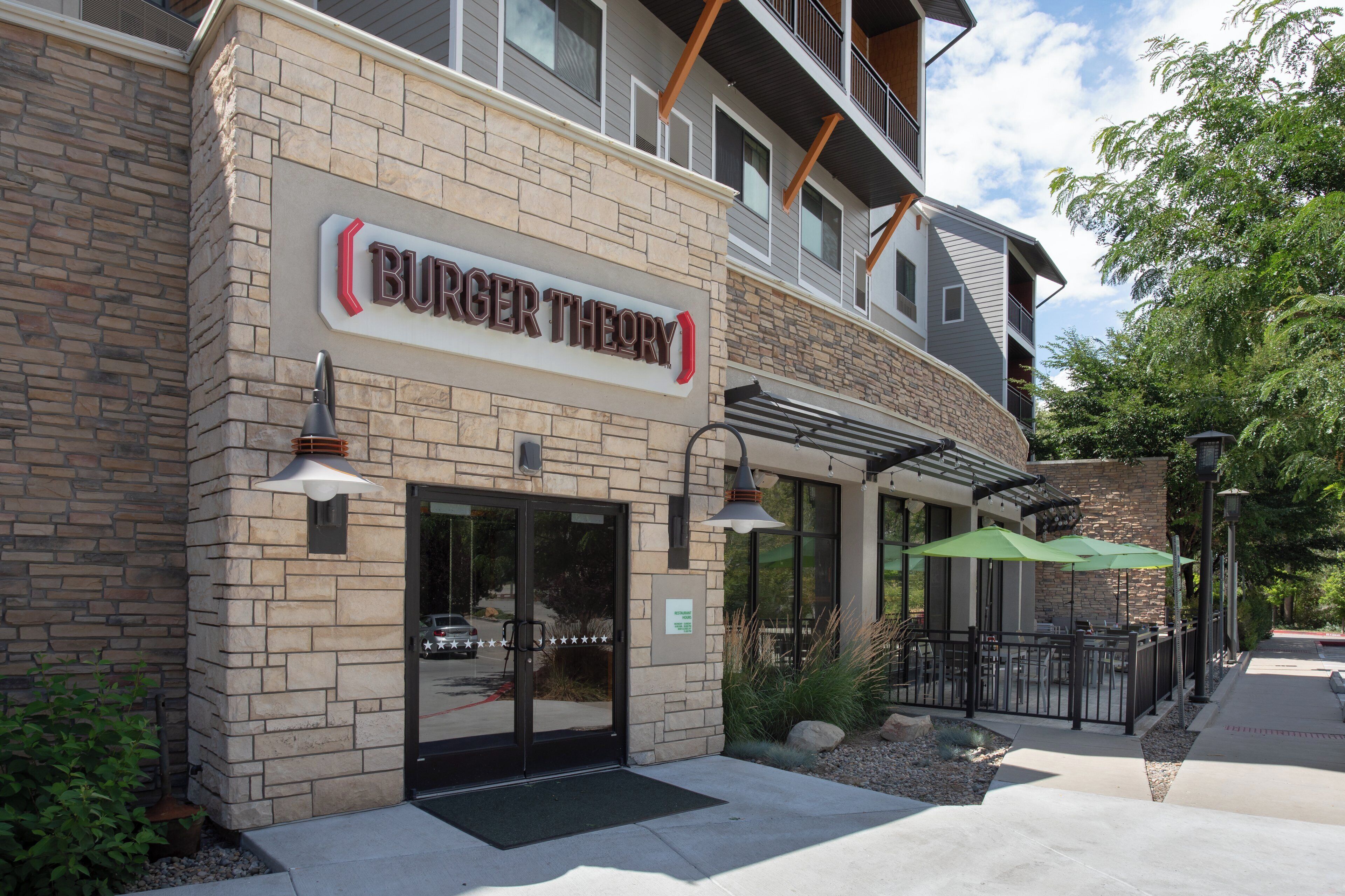 Un restaurant Burger Theory amb façana de pedra, seients exteriors i entrada ben visible.