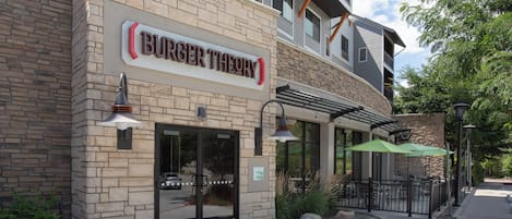 A Burger Theory restaurant with a stone facade, outdoor seating, and a visible entrance.