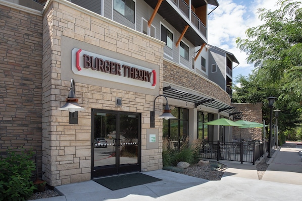 A Burger Theory restaurant with a stone facade, outdoor seating, and a visible entrance.