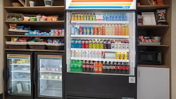 A vending machine stocked with various beverages and snacks, with adjacent refrigerated display cases.