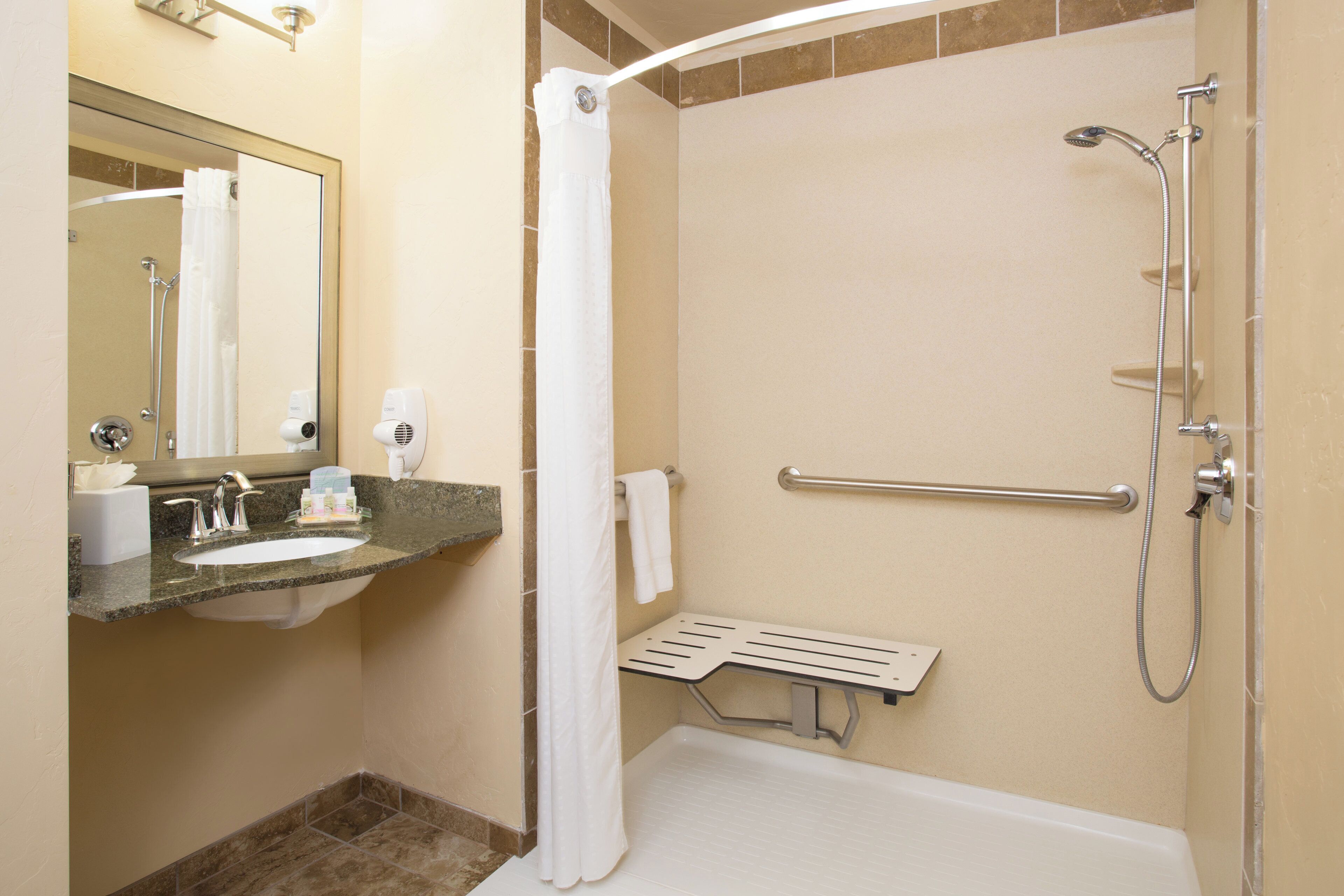 A bathroom with a shower, a sink, and a mirror.