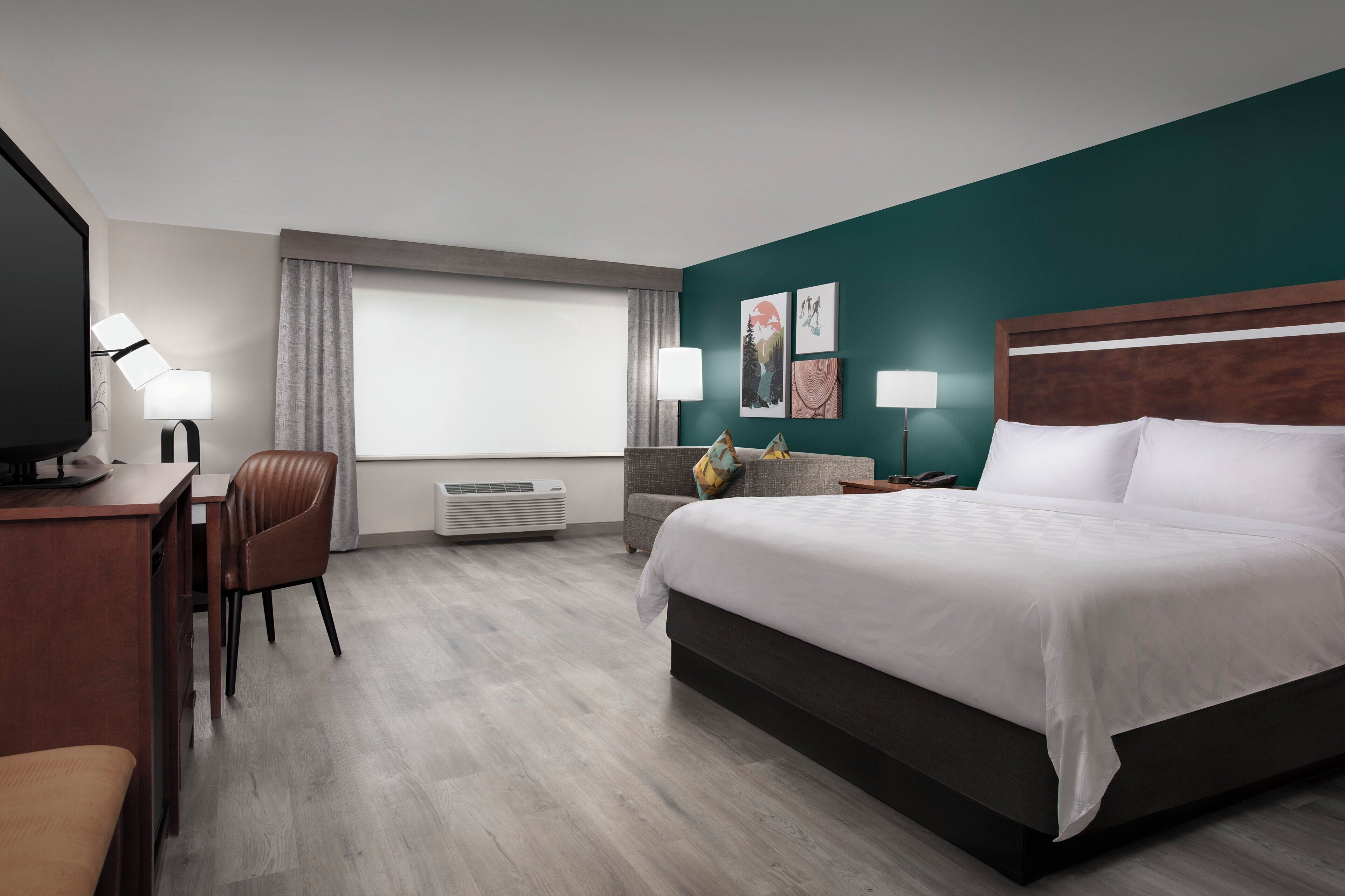 Una habitación de hotel con cama, escritorio, silla y televisor.