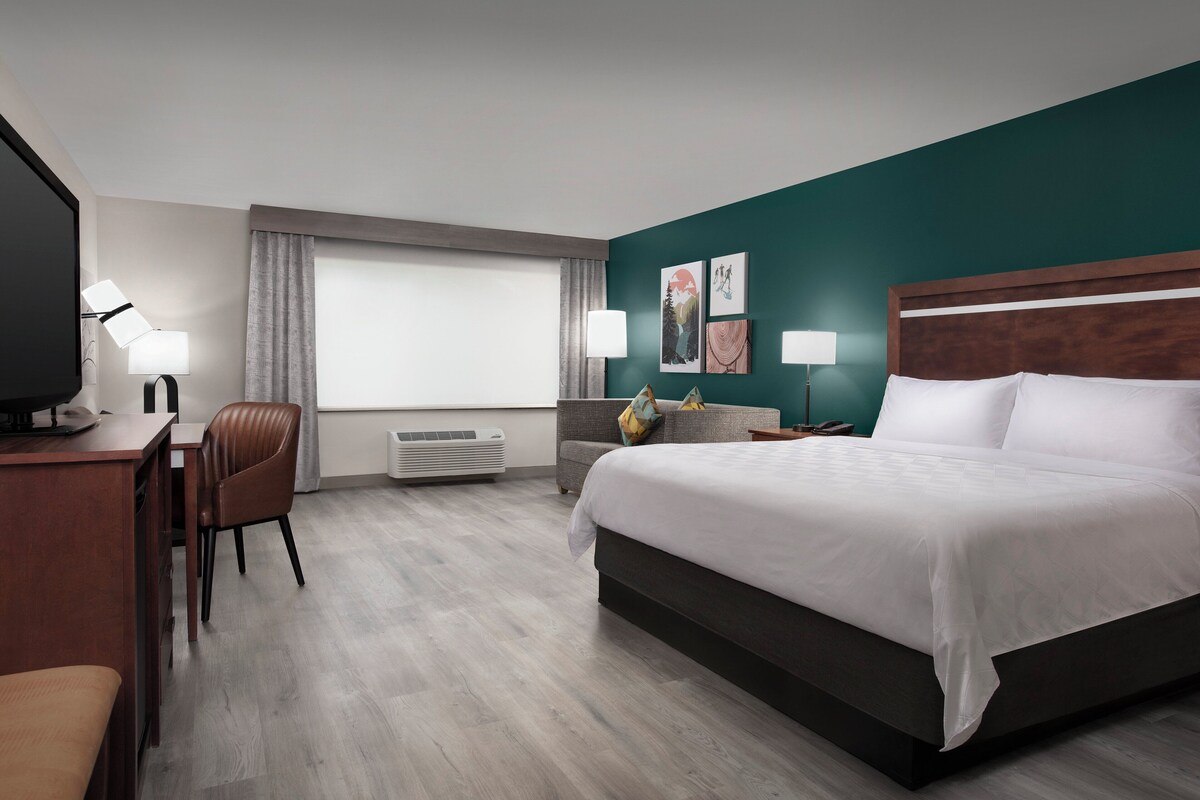 Ein Hotelzimmer mit Bett, Schreibtisch, Stuhl und Fernseher.
