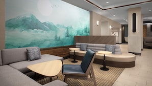 A modern lounge area with a large mural of a mountain landscape, seating arrangements, and a wooden coffee table. - Holiday Inn Hotel & Suites Durango Downtown by IHG (Durango)