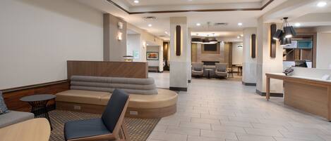 A spacious lobby with a seating area, a reception desk, and a dining area.