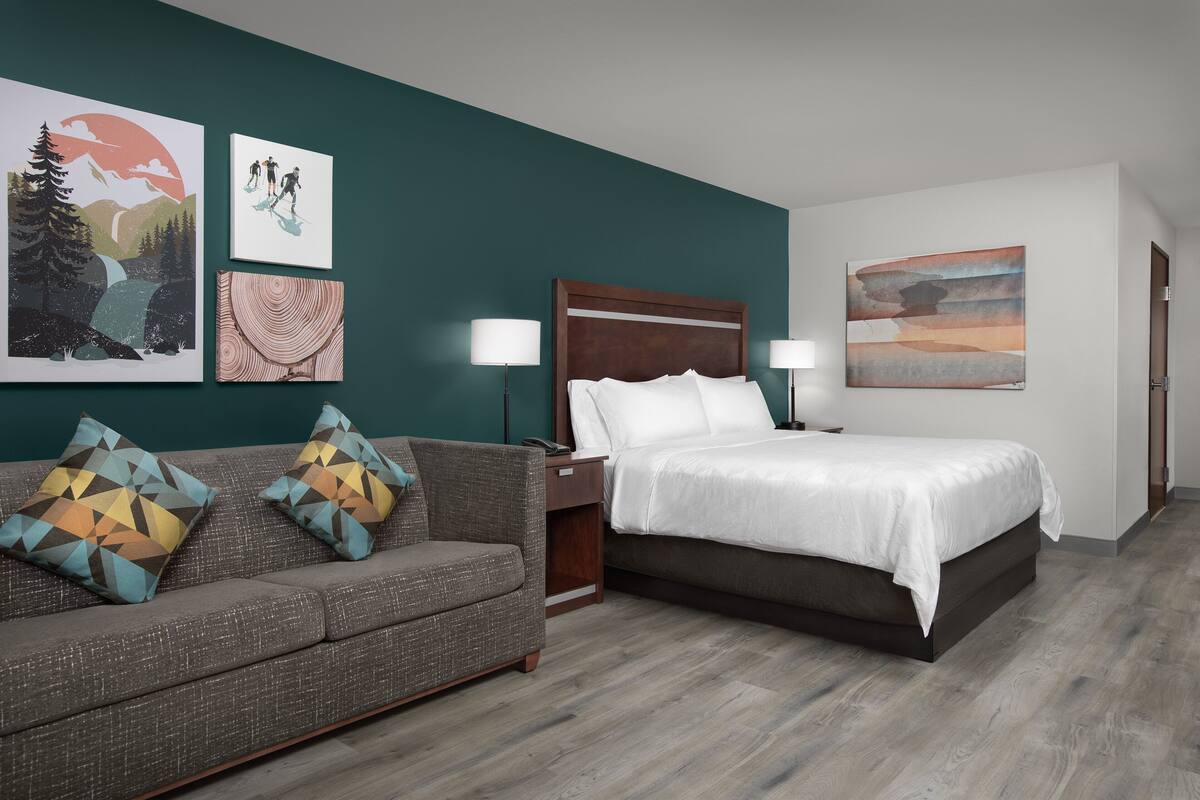 Una habitación de hotel con una cama, un sofá y dos lámparas fijadas a la pared.
