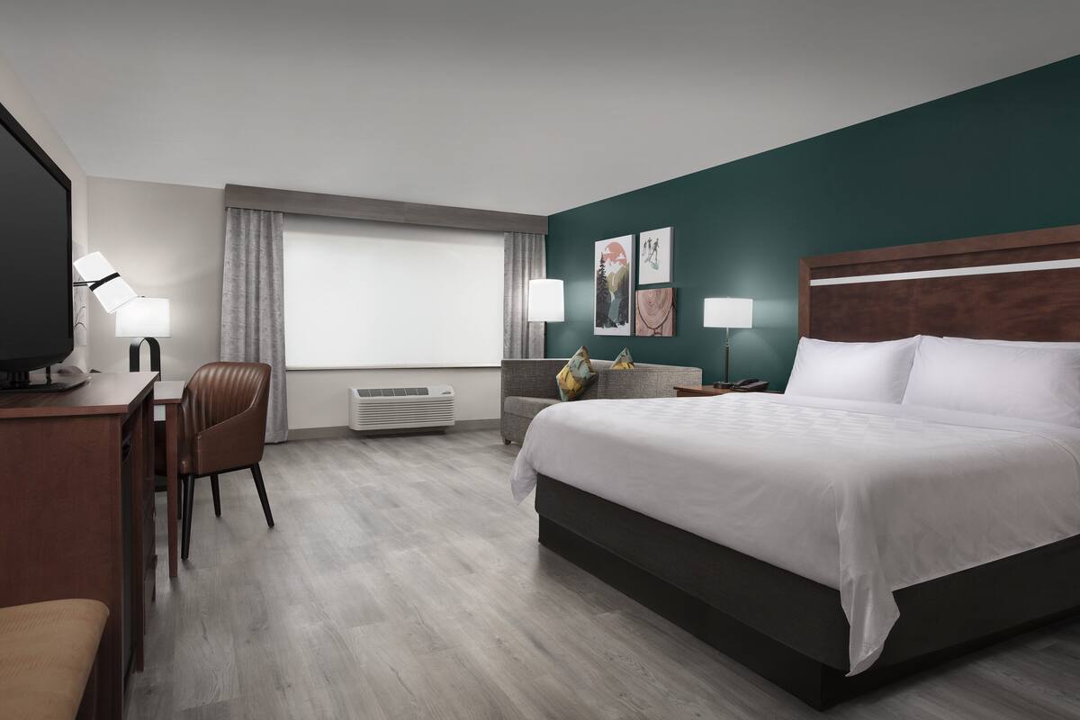 Una habitación de hotel con cama, escritorio, silla y televisor.