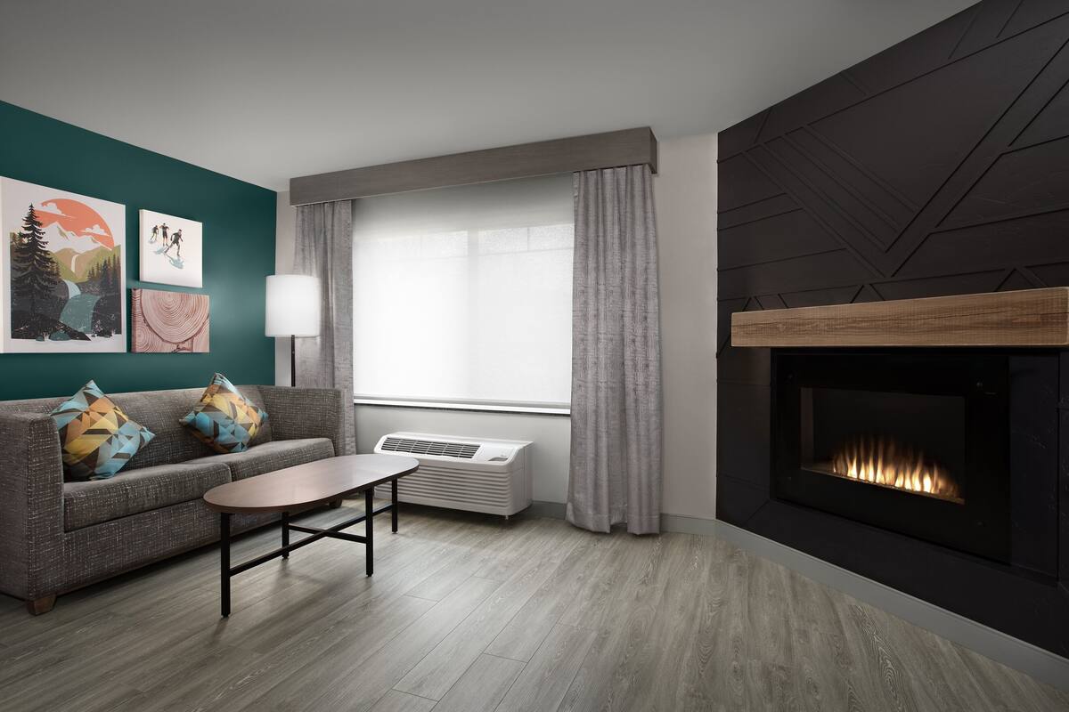 Una sala de estar moderna con un sofá gris, una mesita de centro, una chimenea y obras de arte en la pared.