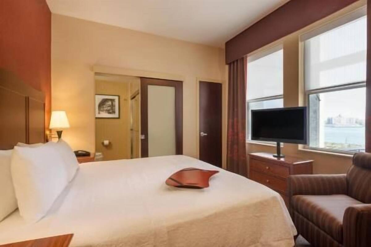A hotel room with a bed, a television, a chair, and a window with a view.