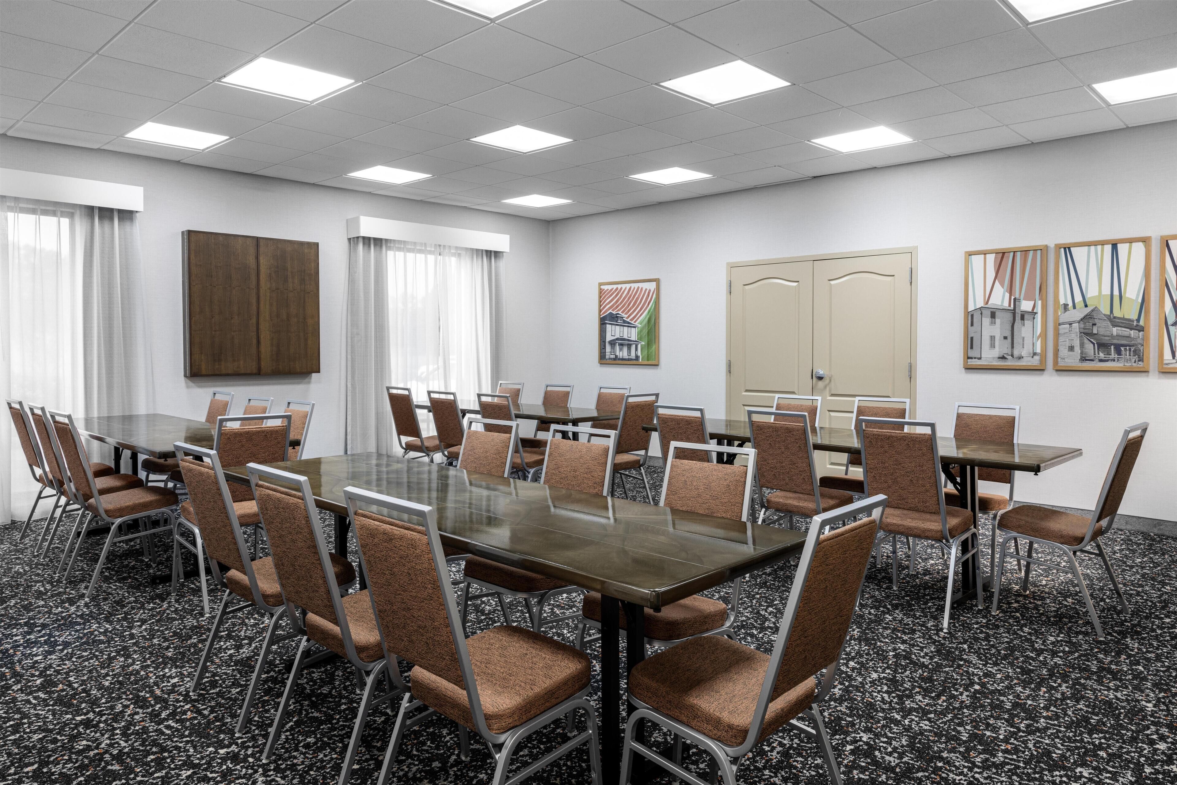 A conference room with a large table, multiple chairs, and a carpeted floor.