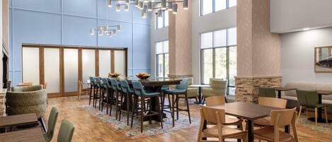 A spacious dining area with high ceilings, large windows, and a modern chandelier.