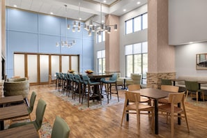 A spacious dining area with high ceilings, large windows, and a modern chandelier.