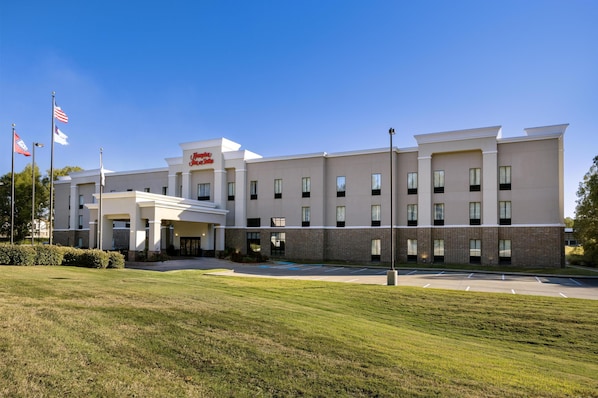 A modern hotel with a flat roof, multiple windows, and a parking lot.
