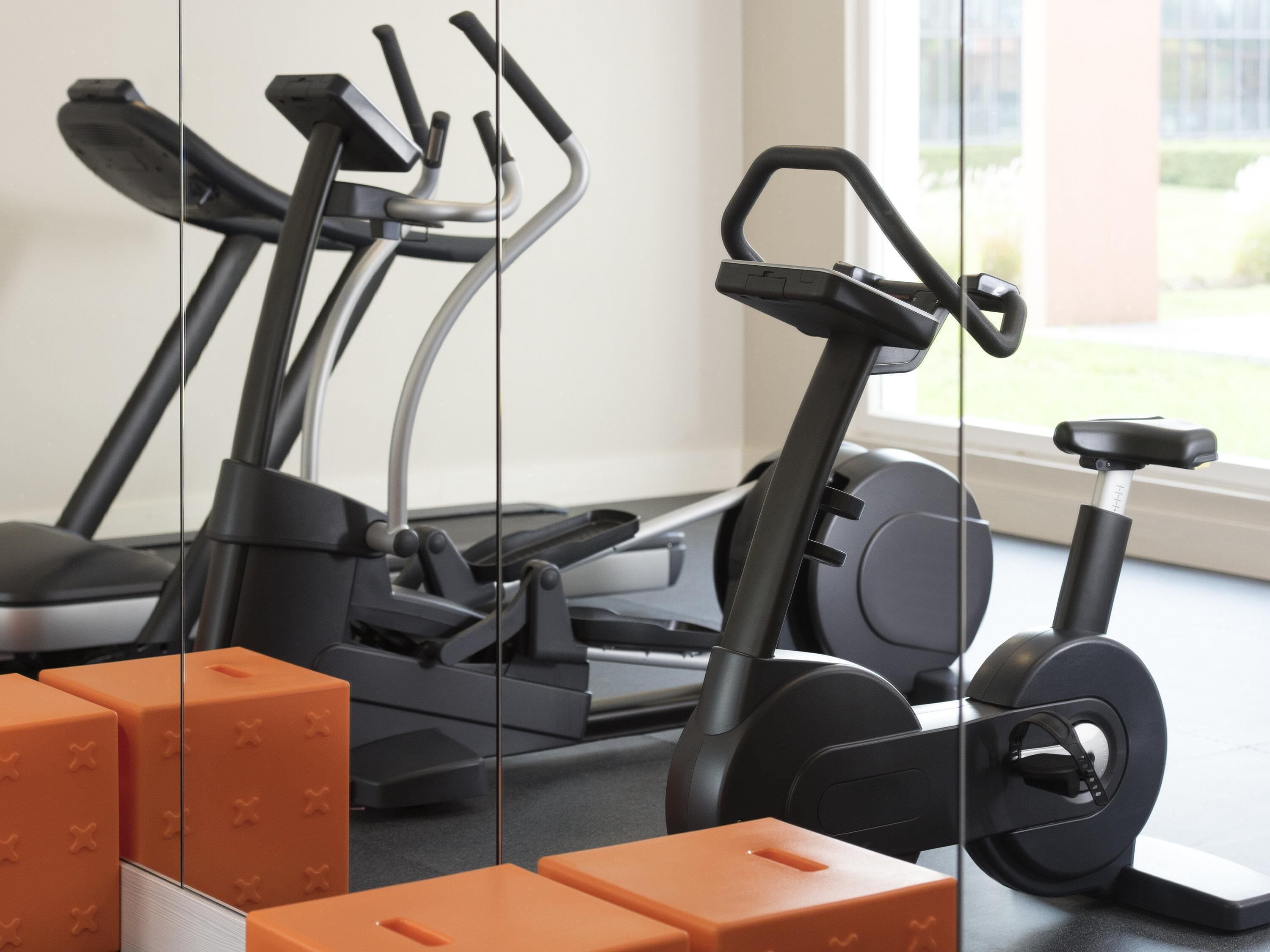 A home gym with exercise equipment including a treadmill, elliptical, and stationary bike.