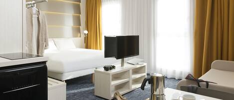 A hotel room with a bed, a TV, a coffee maker, a desk, and a chair.