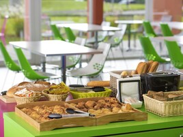 Un bufé de desayuno con diversos pasteles y pan, dispuesto sobre una mesa verde con cestas de mimbre.
