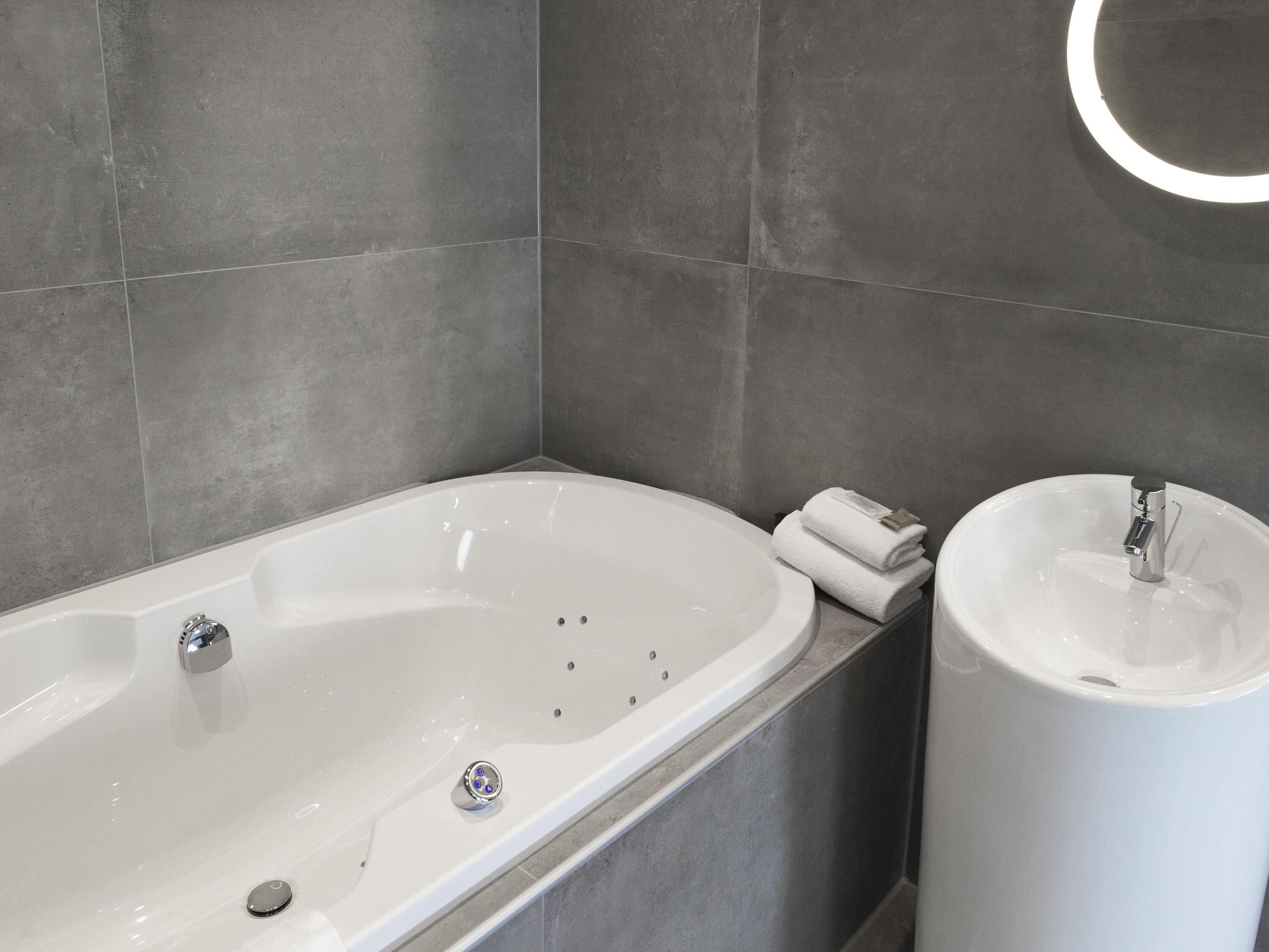 A modern bathroom with a bathtub, a sink, and a towel rack.